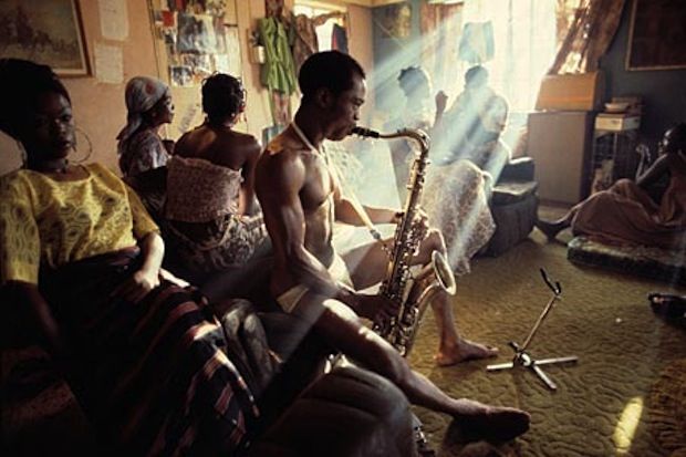 a group of people sitting in a living room next to each other and playing instruments