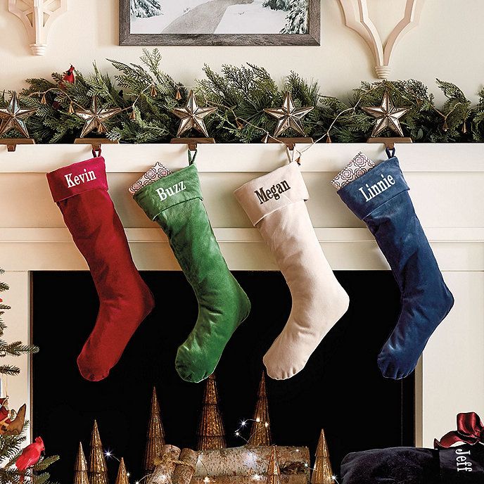 three stockings hanging from a mantel with christmas decorations around them and an ornament on the mantle