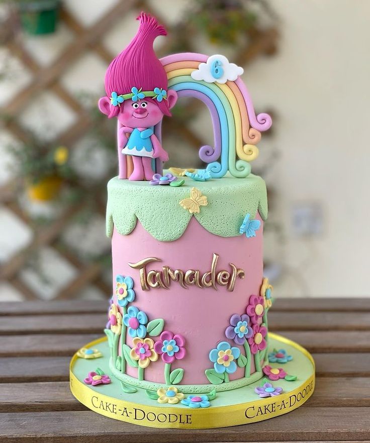 there is a cake decorated with flowers and a pink troll on the top that says tamer