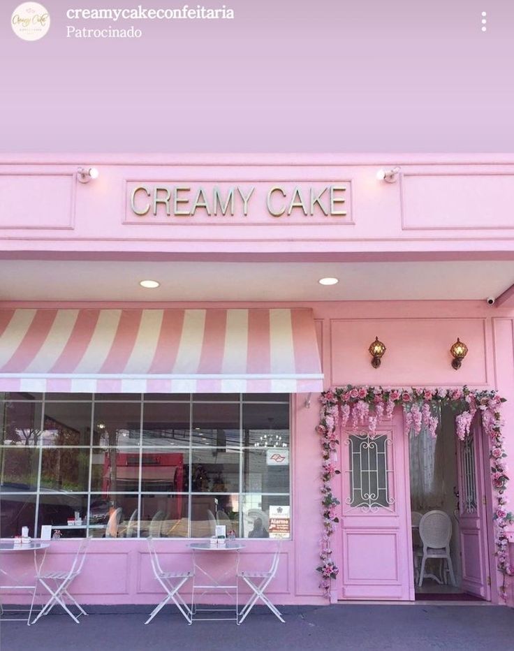 a pink store front with white chairs and flowers on the outside wall, along with an awning that says creamy cake