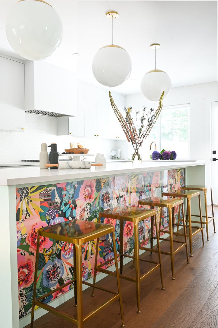 a kitchen with floral wallpaper and gold stools