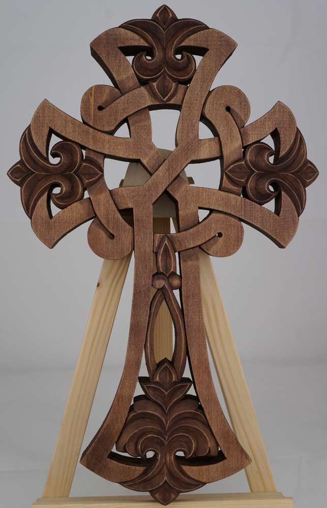 an intricate wooden cross is displayed on a stand