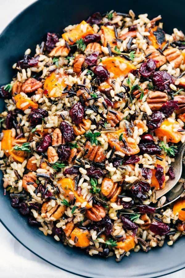 a bowl filled with rice, nuts and dried cranberries on top of a table