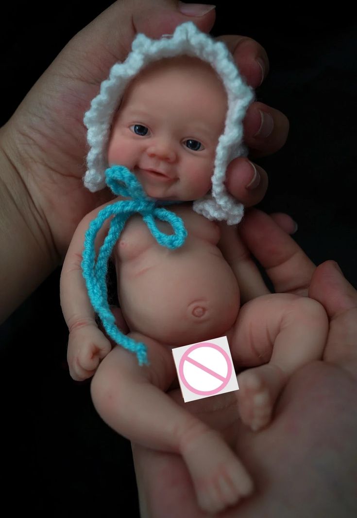 a person holding a small baby doll in their hands with a no sign on it