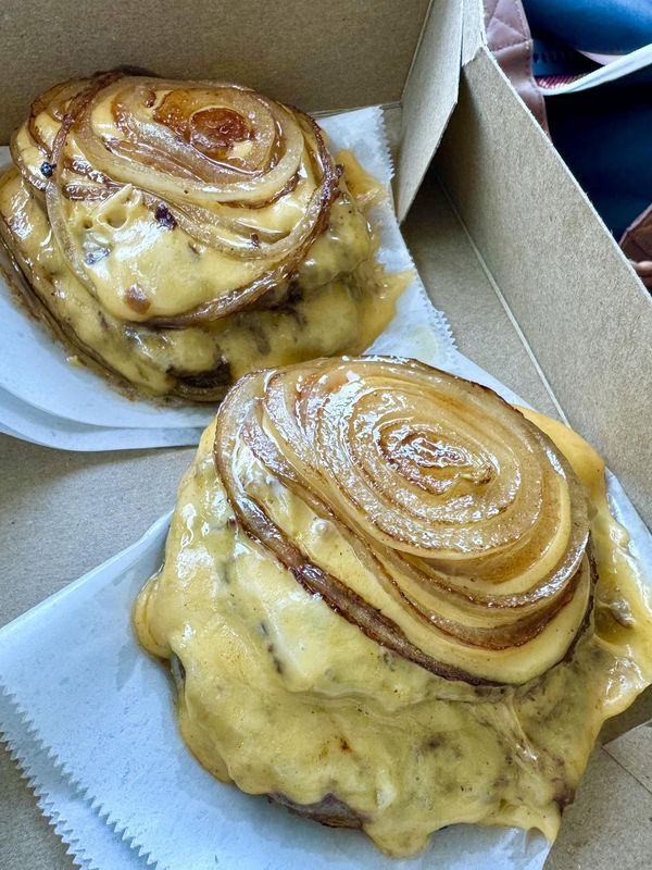 two pastries sitting on top of white paper in a box with yellow icing