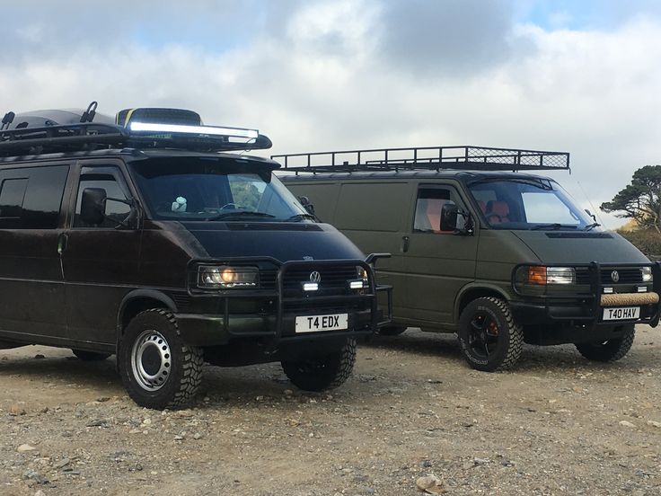 two vans parked next to each other in the dirt