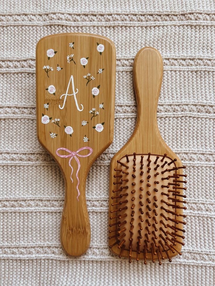 two wooden brushes sitting next to each other on top of a white cloth covered surface