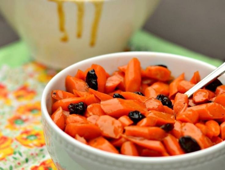 a white bowl filled with carrots and raisins on top of a table