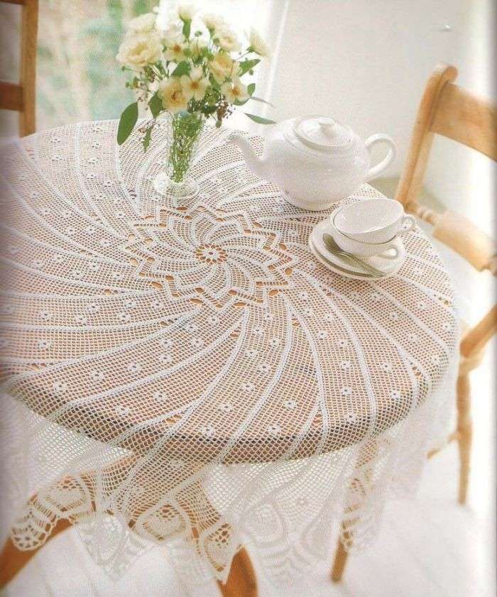 a table topped with a vase filled with flowers next to a cup and saucer