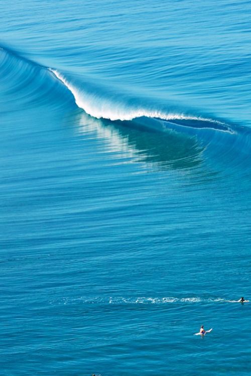 two surfers are riding the waves on their surfboards in the ocean while one is swimming