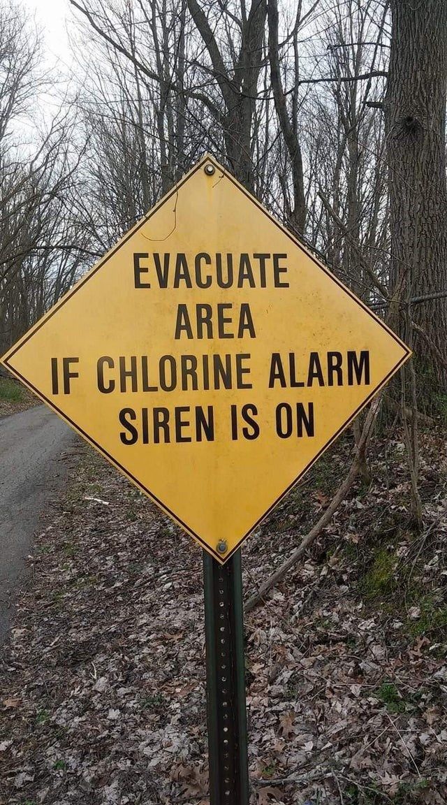 a yellow sign that says evaculate area if chlorine alarm siren is on