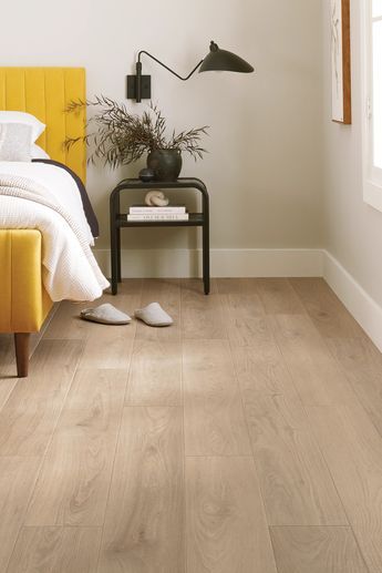 a bedroom scene with focus on the bed and wooden flooring that has been painted white