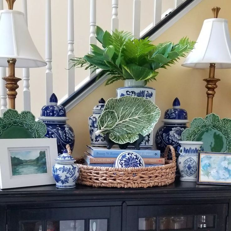 a table topped with blue and white vases next to a bannister filled with plants