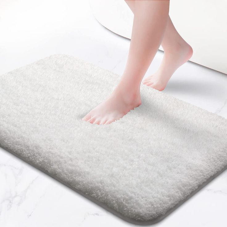 a person is standing on a white bath mat