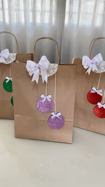 three brown paper bags with christmas ornaments hanging from the handles and bows on each bag