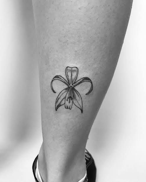 a black and white photo of a woman's foot with a flower tattoo on it