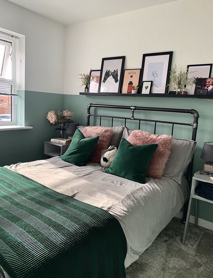 a bedroom with green and white bedding, pictures on the wall above the bed