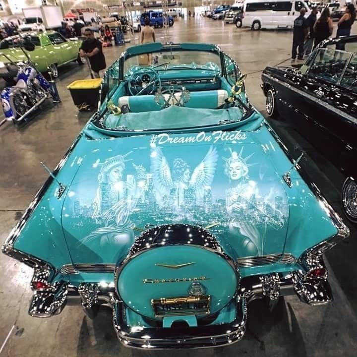 several classic cars are on display in a showroom with people looking at them from the back