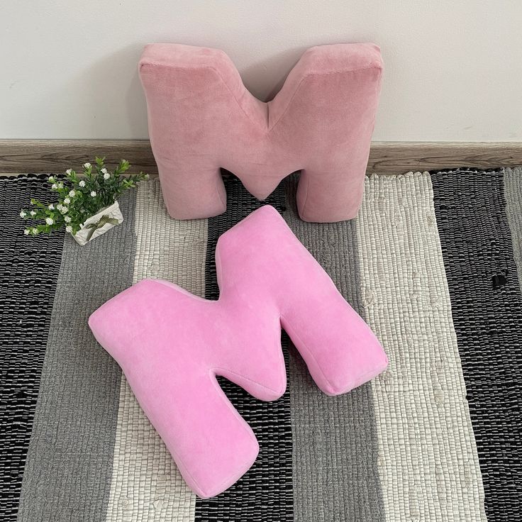 two pink pillows sitting on top of a rug next to a vase with baby's breath flowers