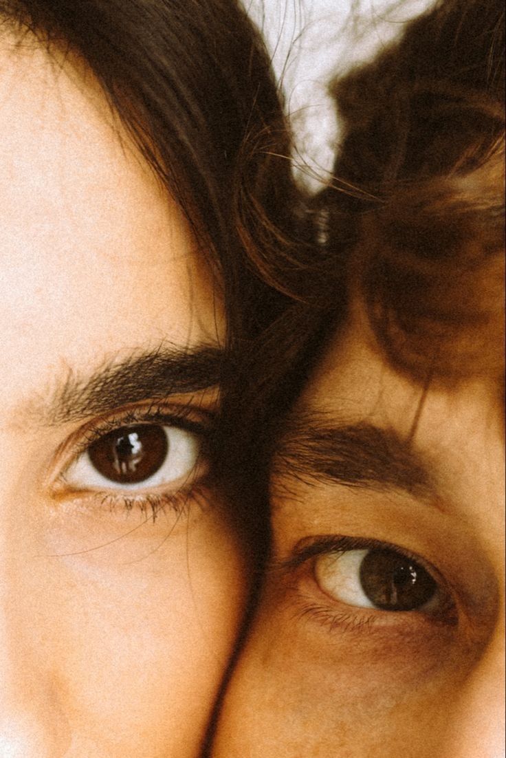 a close up of two people's eyes, one with long hair and the other without