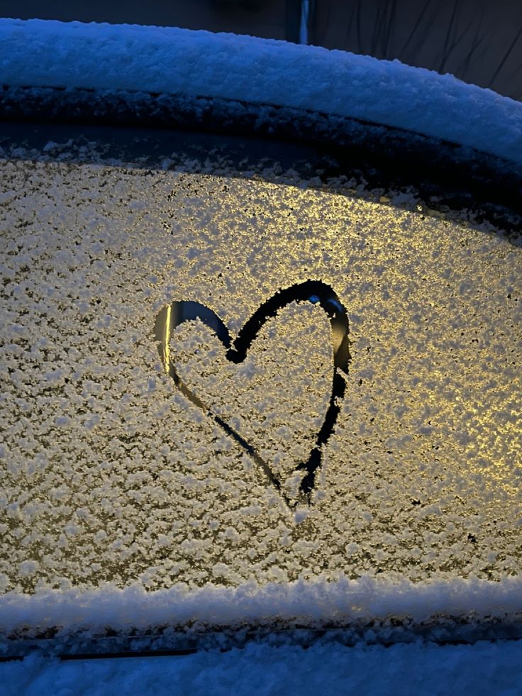 a heart drawn on the windshield of a car covered in snow