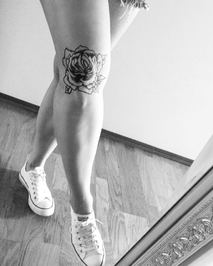 black and white photograph of woman's legs with rose tattoo