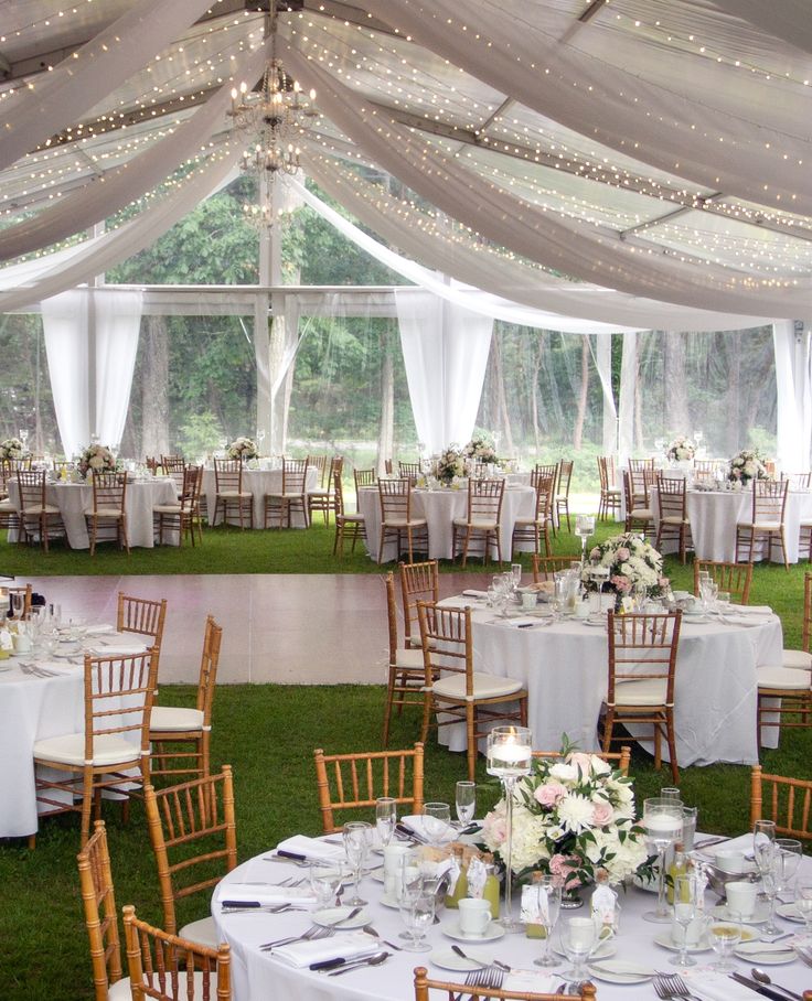 the inside of a tent with tables and chairs set up for a formal dinner party