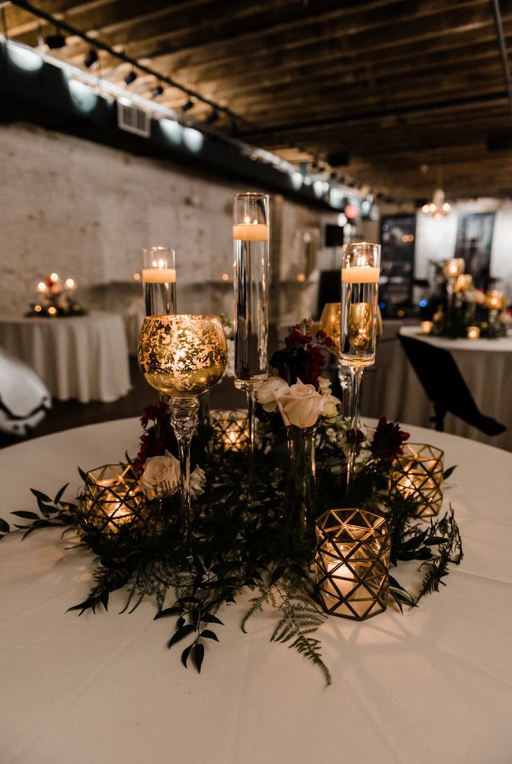 a table topped with candles and flowers on top of a white table cloth covered table