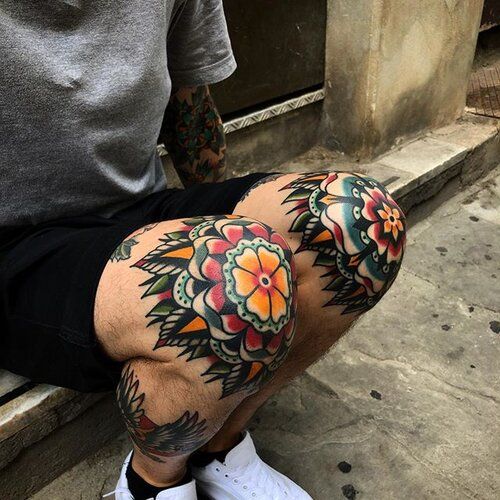 a man with tattoos on his legs and knee is sitting in front of a building