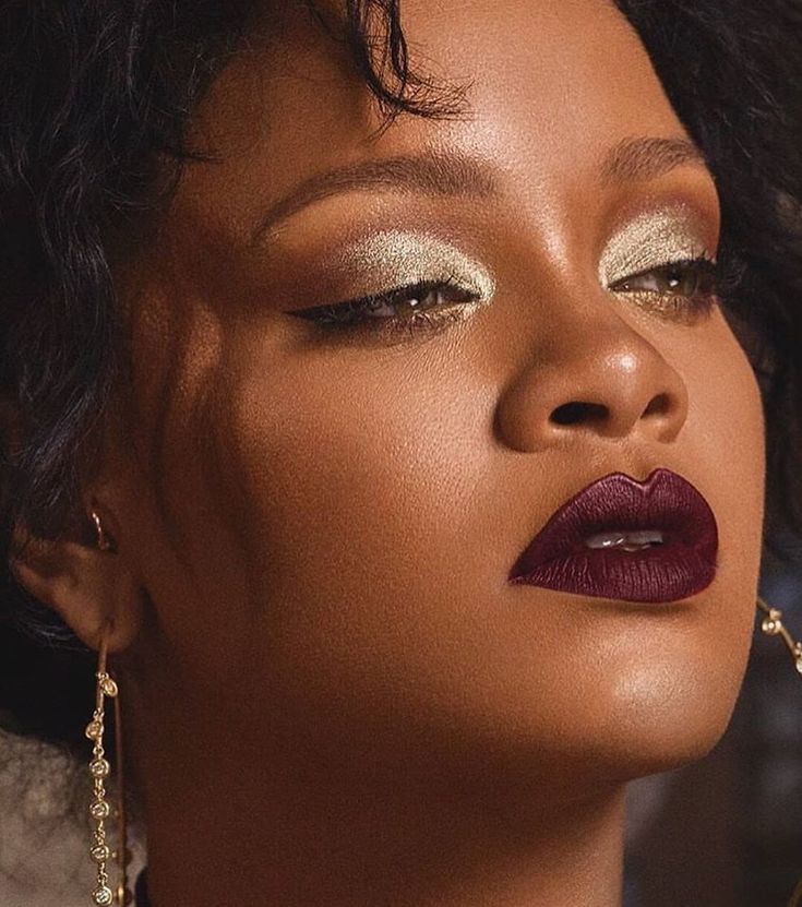 a close up of a woman with makeup on her face and wearing gold necklaces