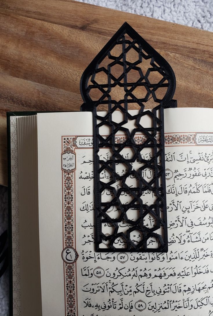 an open book with arabic writing on the pages and a wooden table in the background