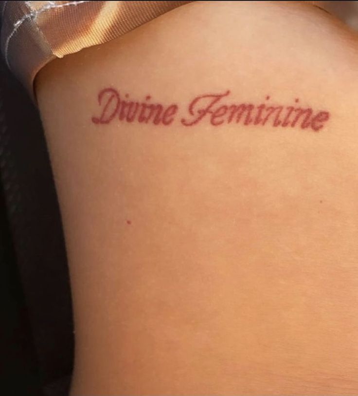 a woman with a tattoo that reads divine feminine