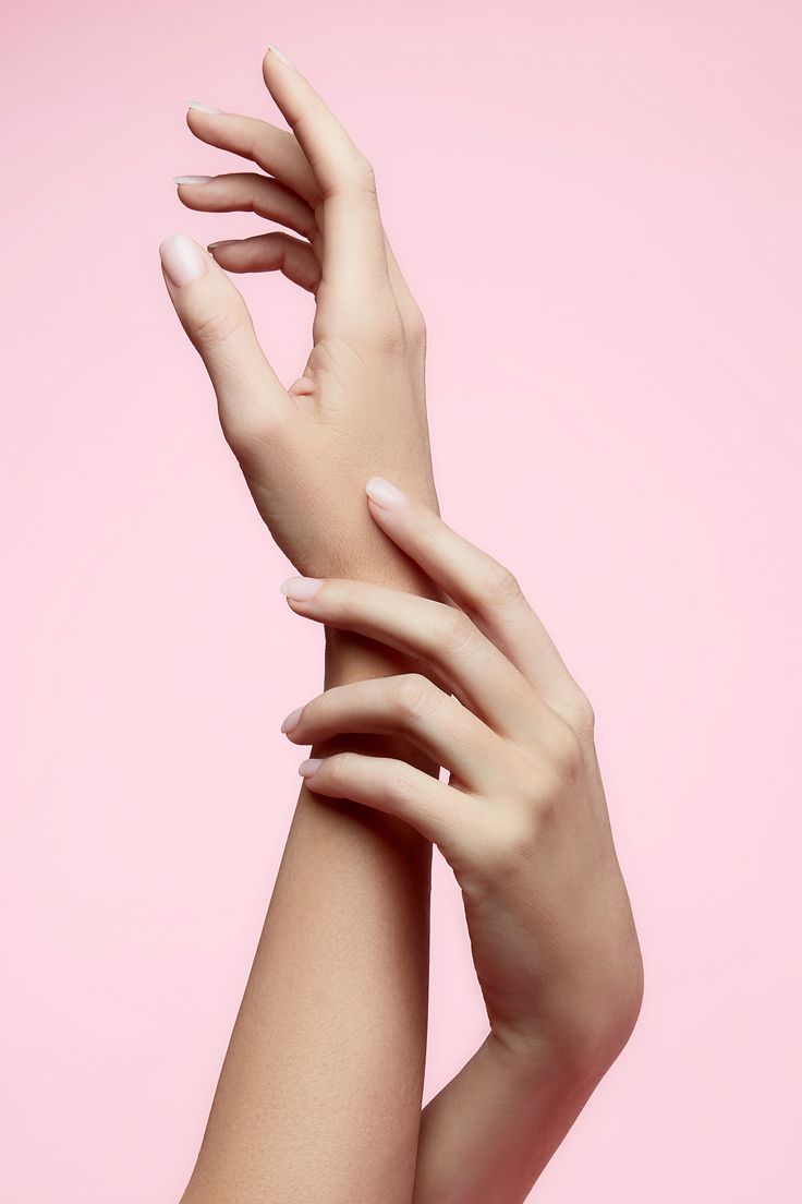 a woman's arm with her hands on top of it, against a pink background