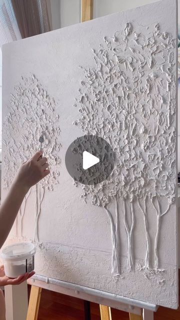 a person is painting on a canvas with white paint