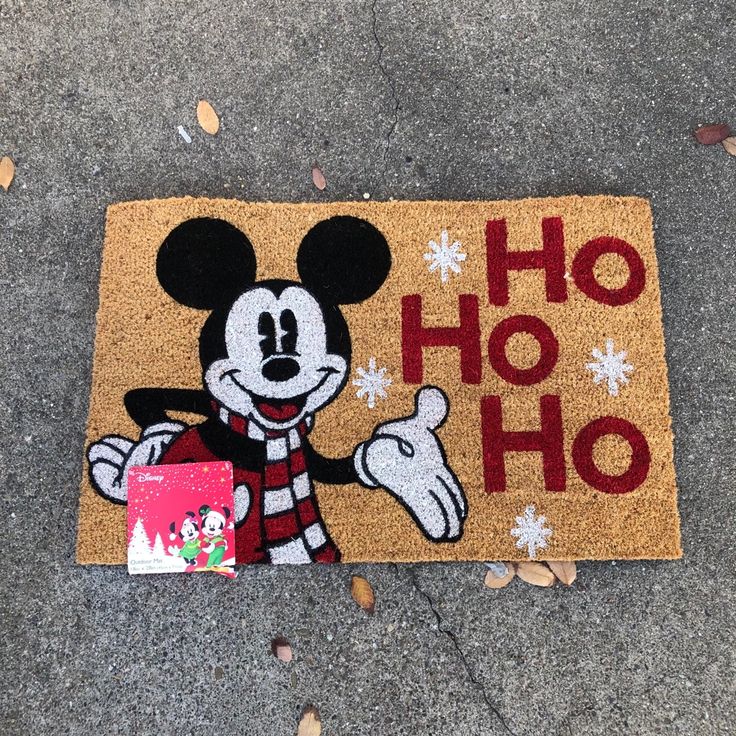 a mickey mouse door mat on the ground with a christmas message in front of it