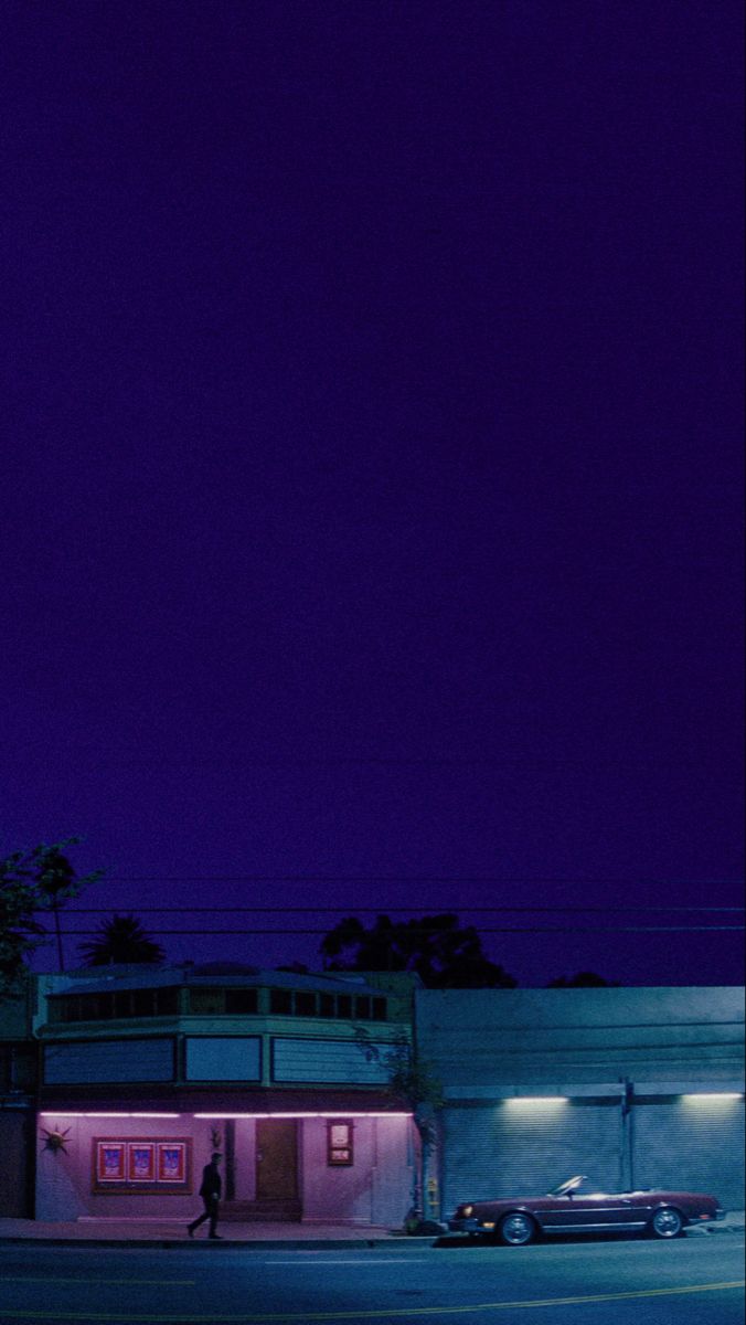 a parking lot at night with a clock tower in the background