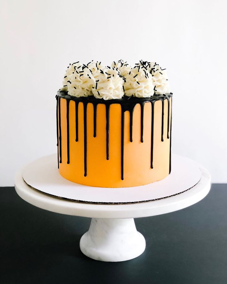 an orange and black drip cake with white frosting