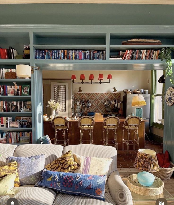 a living room filled with lots of furniture and bookshelves full of books on top of them