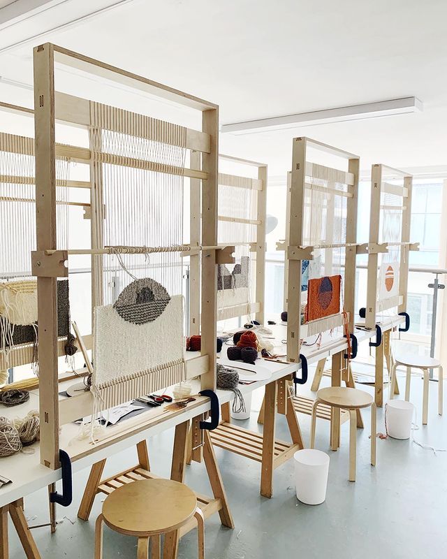 an art studio with several weaving machines and stools