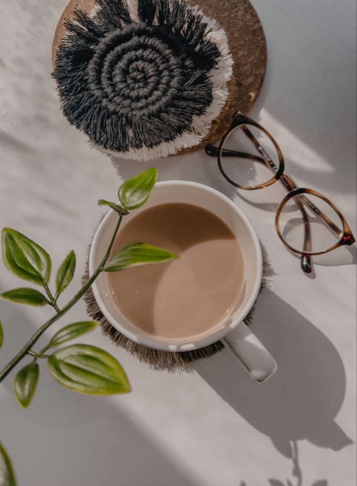 a cup of coffee next to a pair of glasses