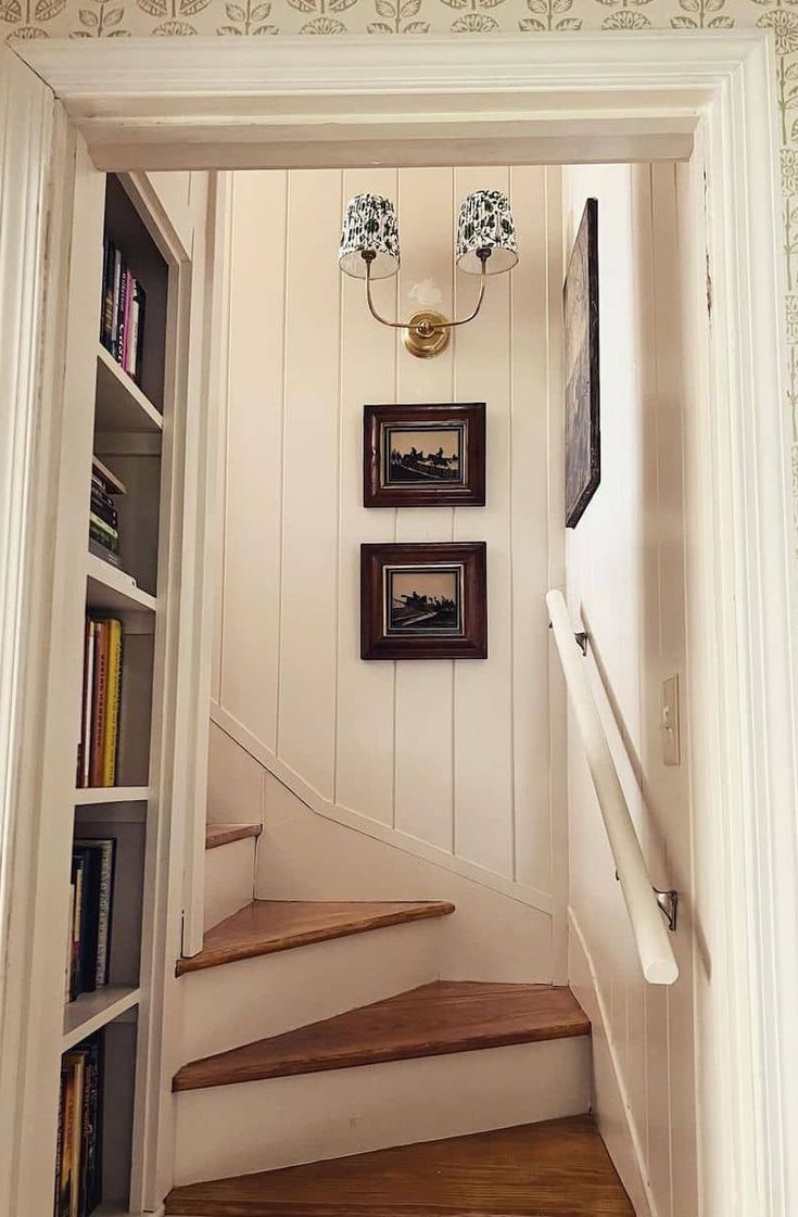 there is a staircase with bookshelves and pictures hanging on the wall above it