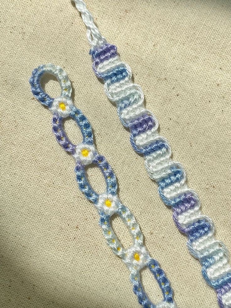 two crocheted bracelets sitting on top of a piece of cloth next to each other