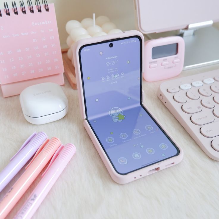 an open cell phone sitting on top of a desk next to a keyboard and mouse