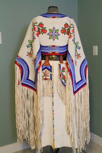 a woman's shawl with fringes and beads on it, in front of a blue wall