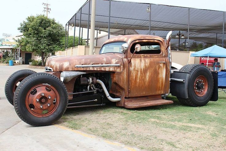 an old rusted car is parked on the grass