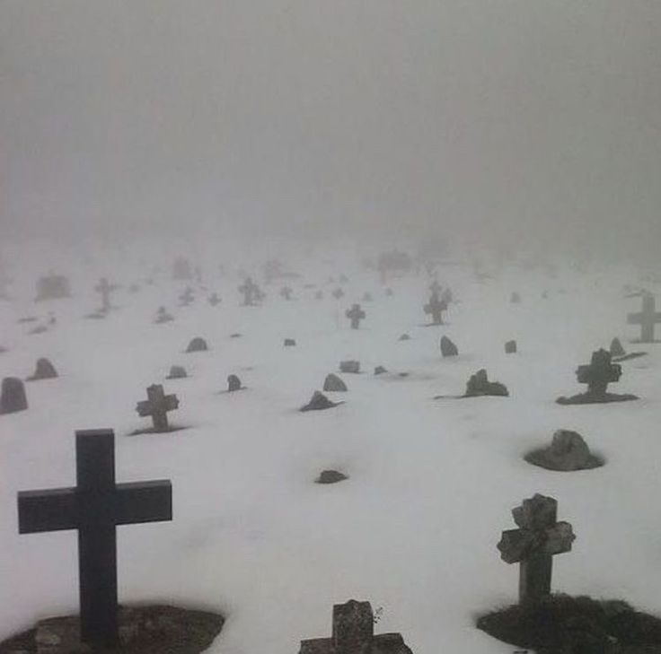 a cemetery covered in snow and lots of crosses