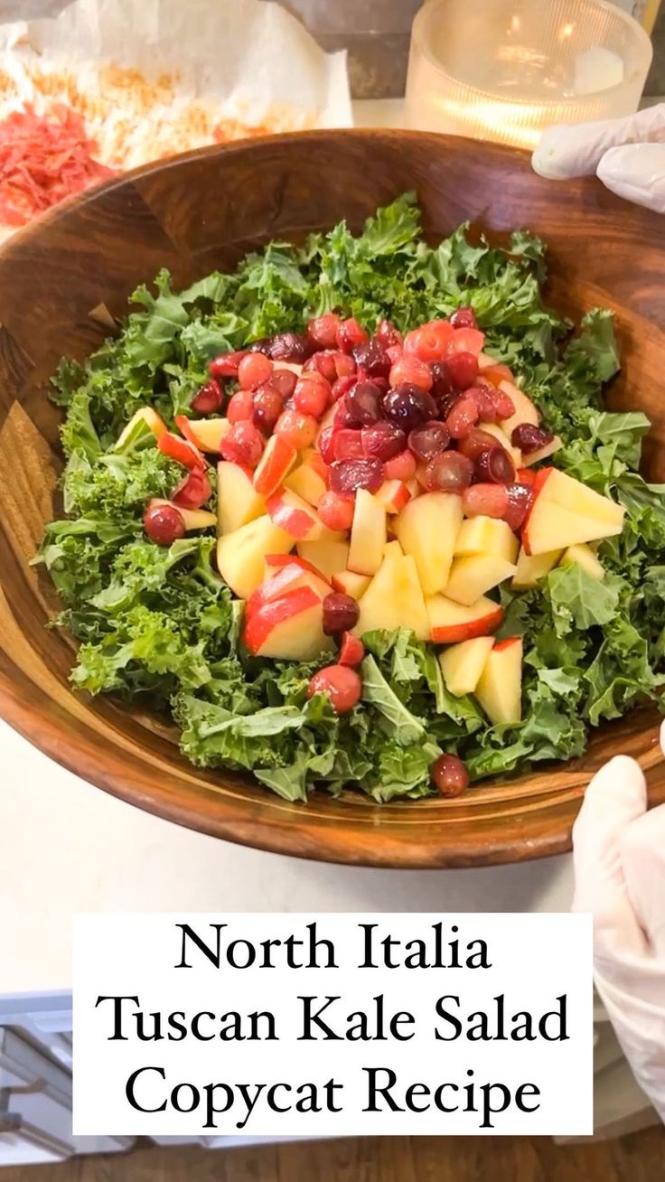 a wooden bowl filled with fruit and vegetables on top of a table next to other food items