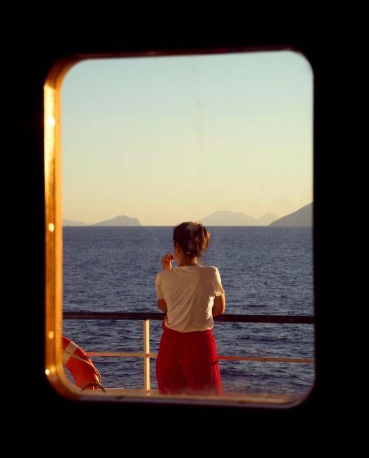 a woman standing on a boat looking out at the ocean