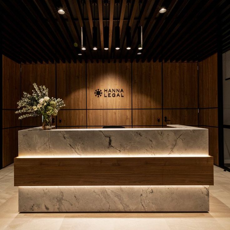 the front desk of an office with flowers in vases and lights on the wall