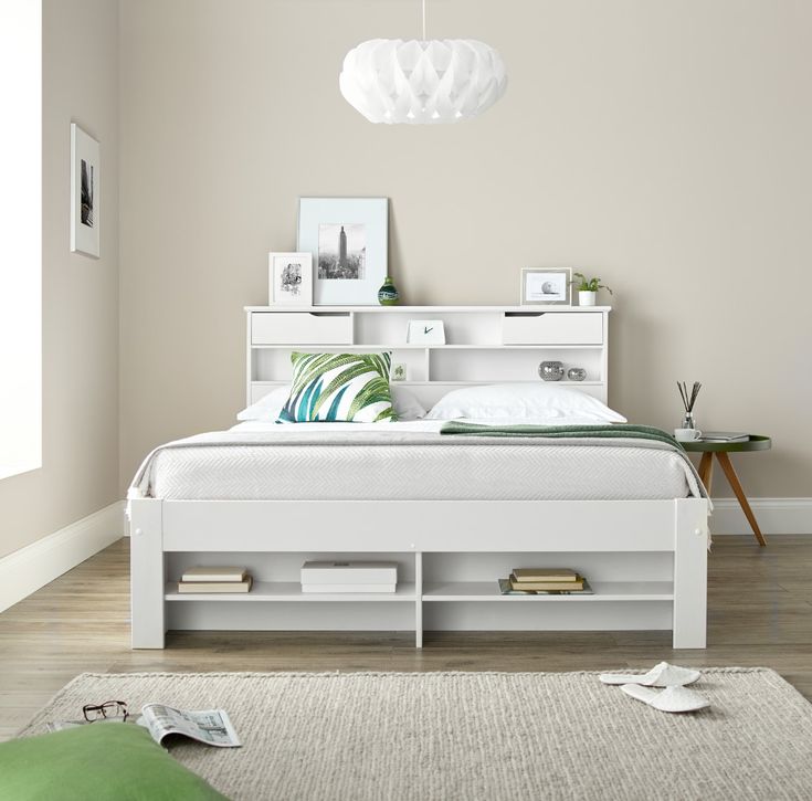 a white bed sitting in a bedroom on top of a hard wood floor